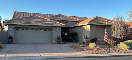 single story home featuring concrete driveway, a tiled roof, an attached garage, and stucco siding