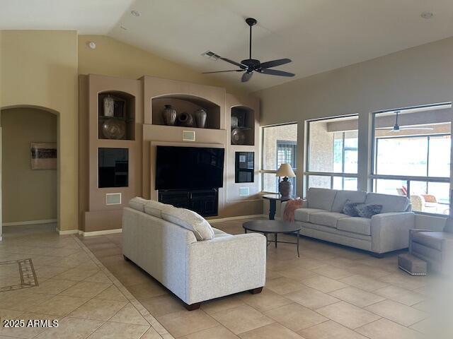 living room featuring arched walkways, vaulted ceiling, ceiling fan, and light tile patterned floors