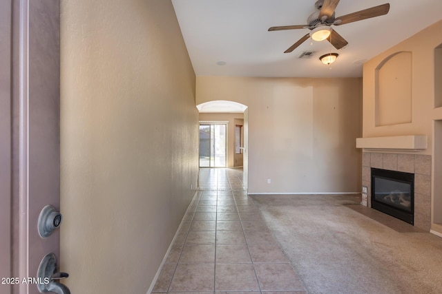 unfurnished living room with ceiling fan, light tile patterned floors, and a fireplace