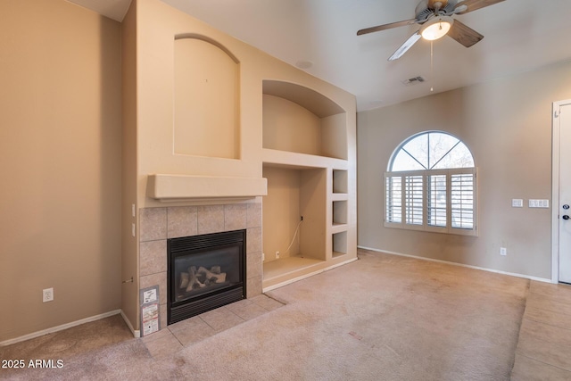 unfurnished living room featuring built in shelves, ceiling fan, a fireplace, and light colored carpet