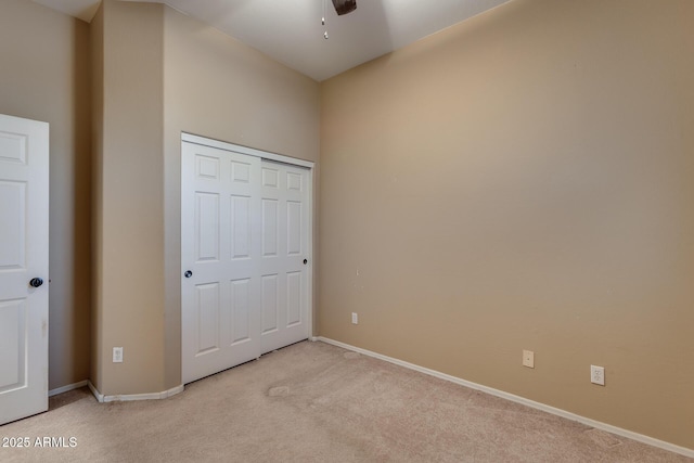 unfurnished bedroom with ceiling fan, light colored carpet, and a closet