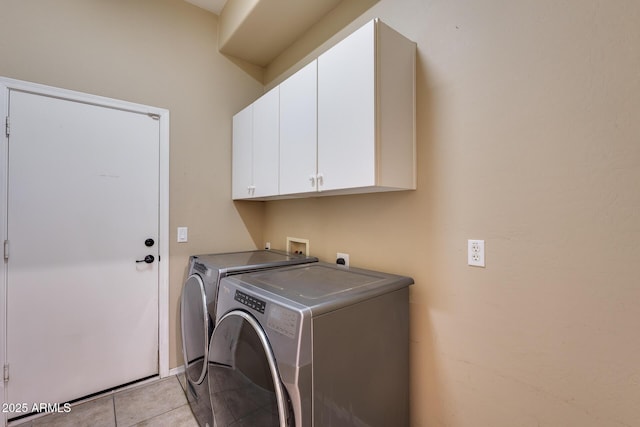 laundry room with washing machine and dryer, light tile patterned floors, and cabinets