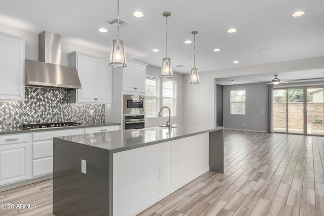 1848 S Follett Way, Gilbert, AZ 85295 - kitchen with wall chimney exhaust hood, stainless steel appliances, a sink, open floor plan, and light wood-style floors