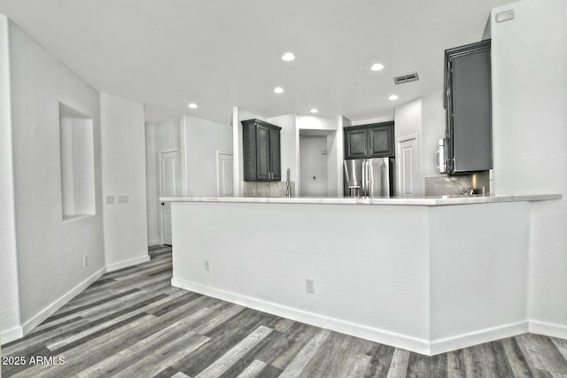 kitchen with kitchen peninsula, stainless steel appliances, dark wood-type flooring, and sink