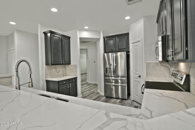 kitchen featuring light stone counters, stainless steel appliances, tasteful backsplash, and dark hardwood / wood-style floors