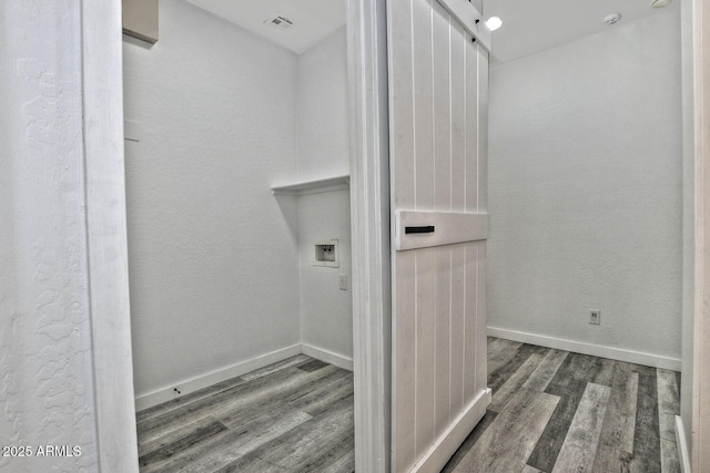 clothes washing area with hookup for a washing machine, a barn door, and dark hardwood / wood-style floors