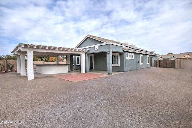 view of front of property featuring exterior bar, a pergola, and a patio