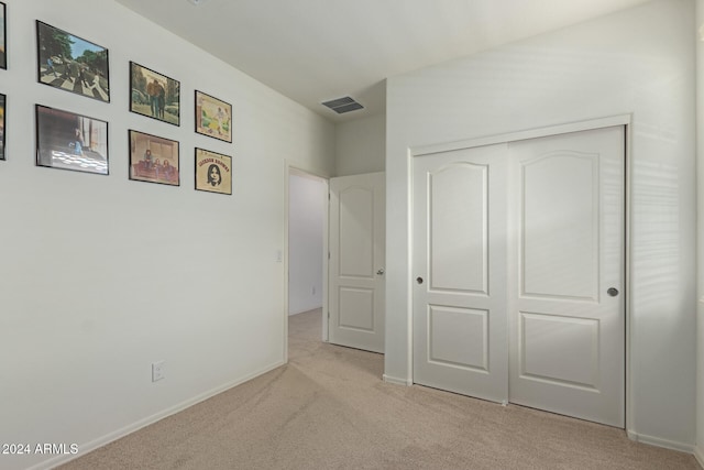 unfurnished bedroom with light carpet and a closet