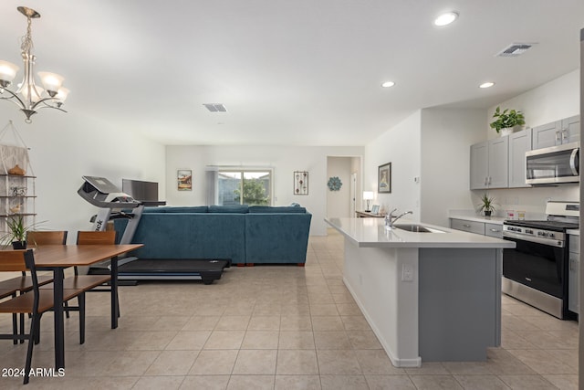 kitchen featuring gray cabinetry, sink, stainless steel appliances, decorative light fixtures, and a kitchen island with sink