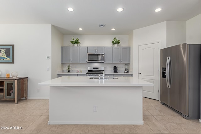 kitchen featuring light tile patterned floors, stainless steel appliances, a kitchen island with sink, and sink