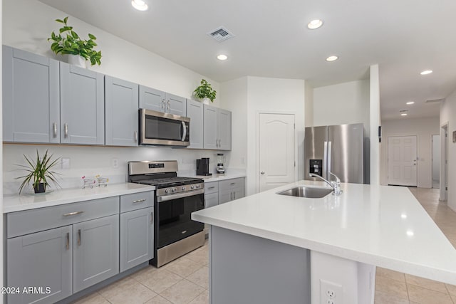 kitchen with a center island with sink, sink, light tile patterned floors, and stainless steel appliances