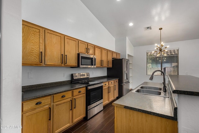 kitchen featuring vaulted ceiling, appliances with stainless steel finishes, pendant lighting, sink, and dark wood-type flooring