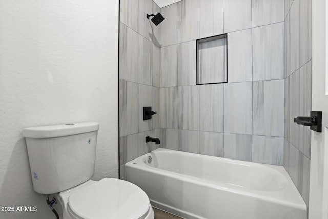 bathroom with tiled shower / bath combo and toilet