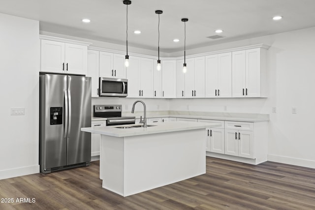 kitchen with sink, appliances with stainless steel finishes, white cabinetry, a center island with sink, and decorative light fixtures