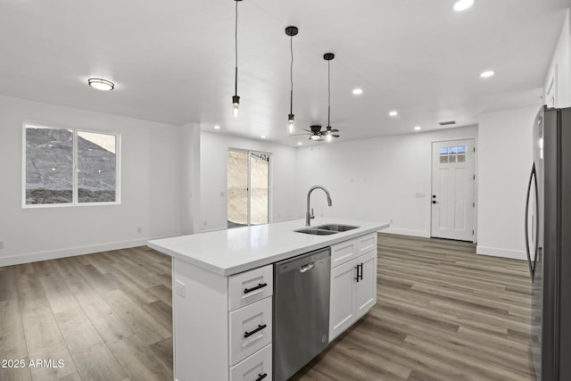 kitchen with appliances with stainless steel finishes, a kitchen island with sink, sink, and white cabinets