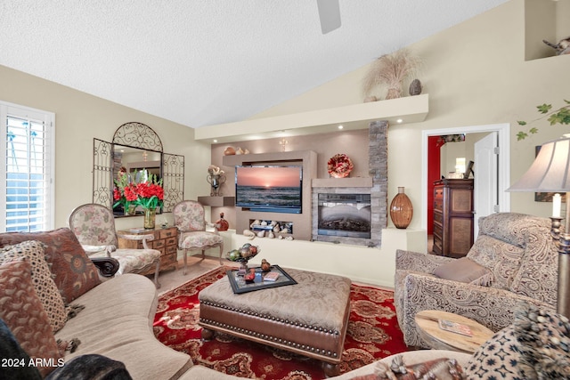 living room with a fireplace, high vaulted ceiling, and a textured ceiling