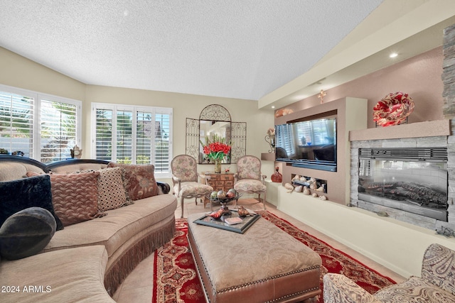 living room with a fireplace, a textured ceiling, and vaulted ceiling