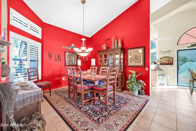 dining space featuring light tile patterned flooring, high vaulted ceiling, and a chandelier