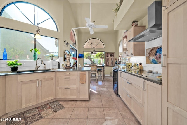 kitchen featuring black electric cooktop, sink, wall chimney range hood, light tile patterned floors, and a high ceiling