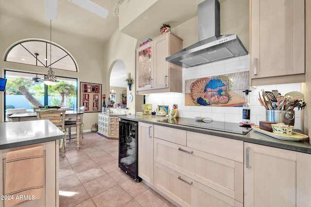 kitchen with hanging light fixtures, wine cooler, wall chimney exhaust hood, tasteful backsplash, and stovetop