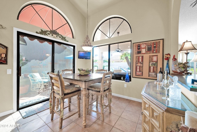 tiled dining room with ceiling fan, plenty of natural light, and high vaulted ceiling