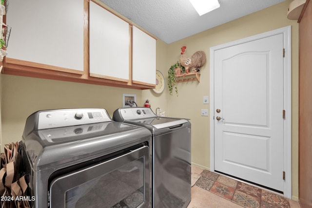 clothes washing area with cabinets, separate washer and dryer, a textured ceiling, and light tile patterned floors