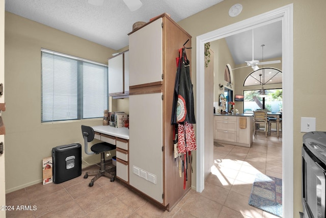 office area with ceiling fan, light tile patterned flooring, a textured ceiling, and vaulted ceiling