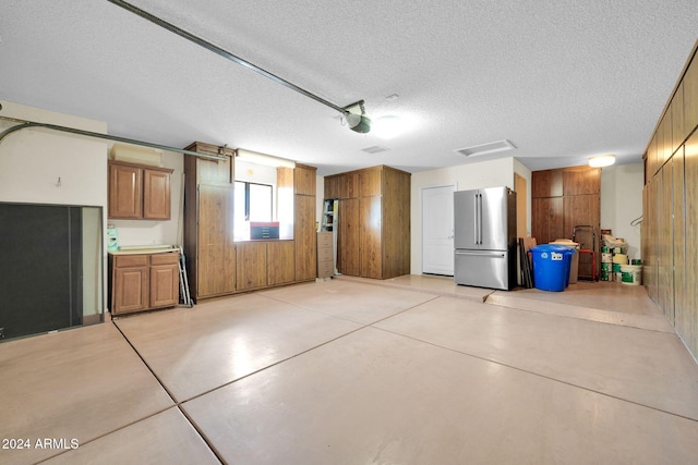 garage featuring a garage door opener, stainless steel refrigerator, and wood walls