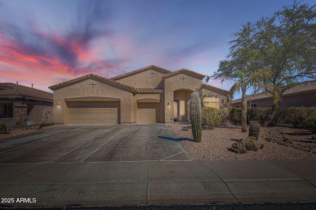 mediterranean / spanish-style home featuring a tile roof, driveway, an attached garage, and stucco siding