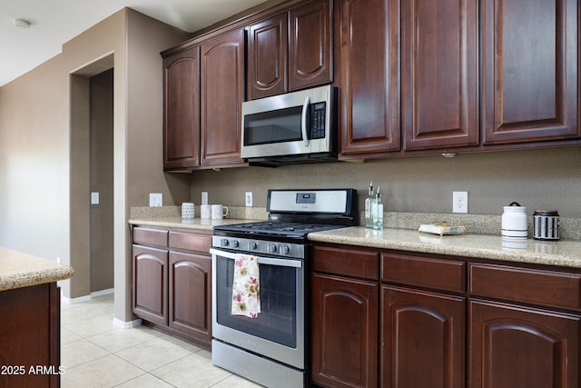2003 Valley Sage St, Sierra Vista, AZ 85635 - kitchen featuring stainless steel appliances, light tile patterned floors, dark brown cabinetry, baseboards, and light stone countertops