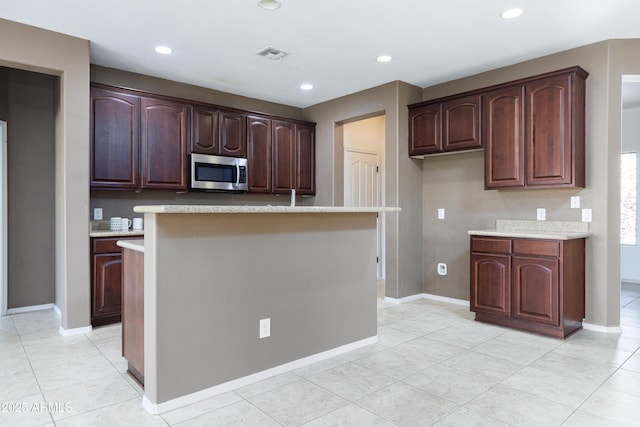 2003 Valley Sage St, Sierra Vista, AZ 85635 - kitchen featuring stainless steel microwave, light tile patterned floors, recessed lighting, dark brown cabinetry, and a kitchen island