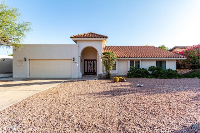 mediterranean / spanish house featuring an attached garage, stucco siding, driveway, and a tile roof