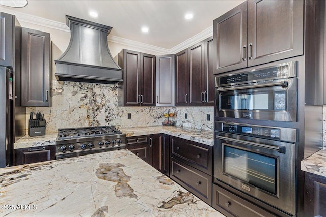 kitchen with stove, stainless steel double oven, backsplash, premium range hood, and crown molding