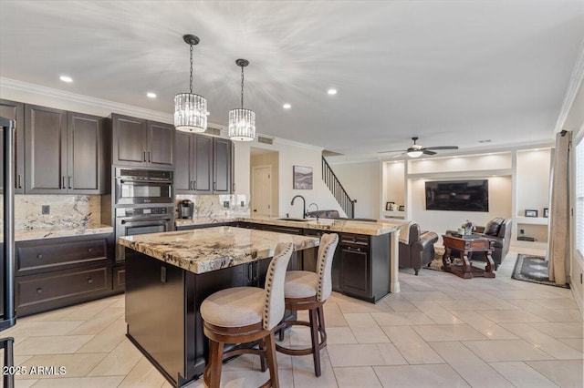 kitchen with a breakfast bar area, hanging light fixtures, a center island, kitchen peninsula, and sink