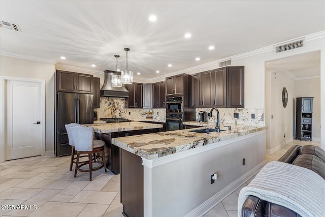 kitchen with stainless steel appliances, sink, decorative light fixtures, custom range hood, and kitchen peninsula