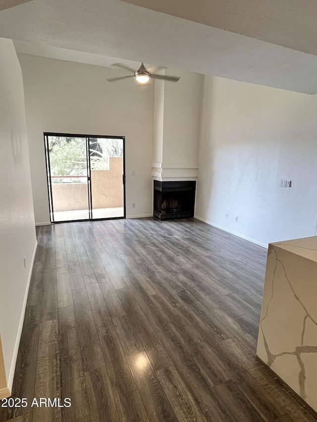 4850 E Desert Cove Ave Unit 241, Scottsdale, AZ 85254 - unfurnished living room featuring dark wood-style flooring, ceiling fan, baseboards, and a fireplace