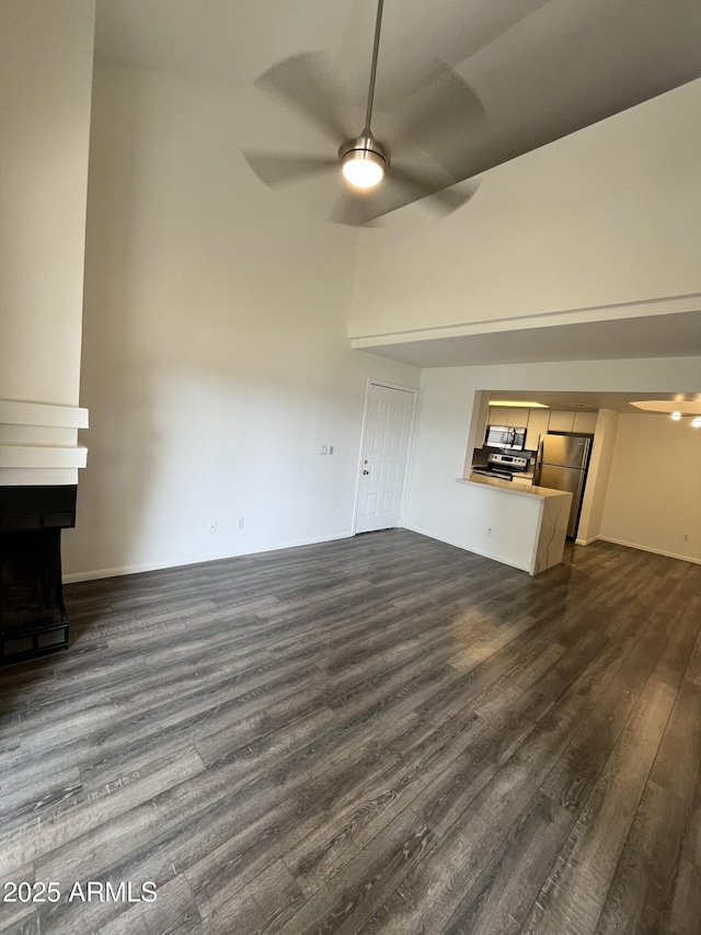 4850 E Desert Cove Ave Unit 241, Scottsdale, AZ 85254 - unfurnished living room featuring dark wood-type flooring, a ceiling fan, a large fireplace, and baseboards