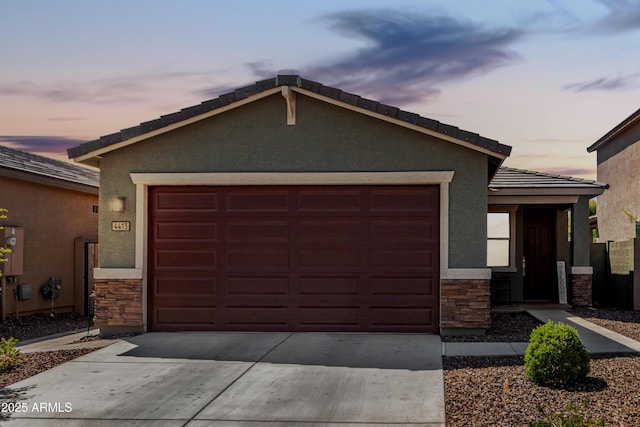 4413 W Samantha Way, Laveen, AZ 85339 - view of front facade with a tiled roof, stone siding, concrete driveway, an attached garage, and stucco siding