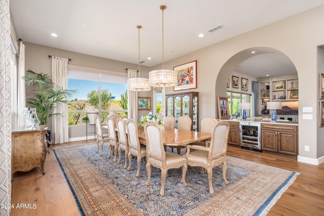 dining area featuring light hardwood / wood-style flooring, beverage cooler, and an inviting chandelier