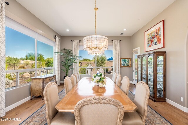 dining room with light wood-type flooring and an inviting chandelier