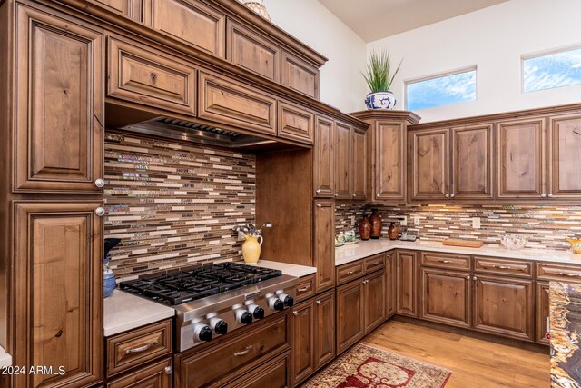 kitchen featuring stainless steel gas stovetop, light hardwood / wood-style floors, and tasteful backsplash