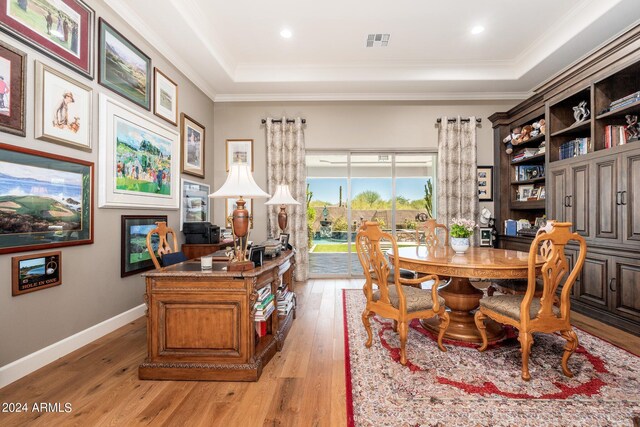 interior space featuring light wood-type flooring, a raised ceiling, and crown molding