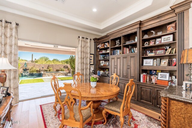 dining space with a tray ceiling, light hardwood / wood-style floors, and crown molding