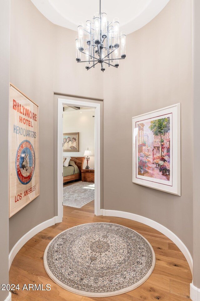 hallway with wood-type flooring and an inviting chandelier