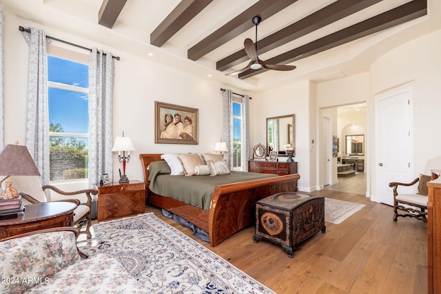 bedroom featuring light hardwood / wood-style floors, ceiling fan, and beamed ceiling