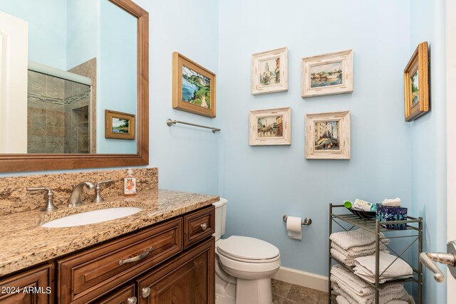 bathroom featuring tile patterned floors, a shower with door, vanity, and toilet