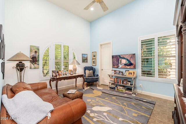 tiled living room with ceiling fan, plenty of natural light, and high vaulted ceiling