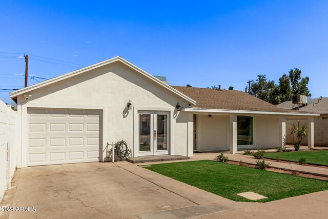 ranch-style house with a garage, a front yard, and central AC unit