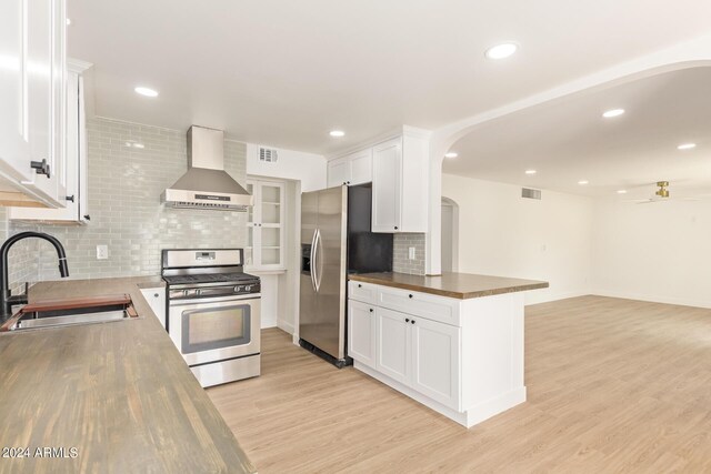 kitchen with white cabinets, stainless steel appliances, sink, and wall chimney range hood