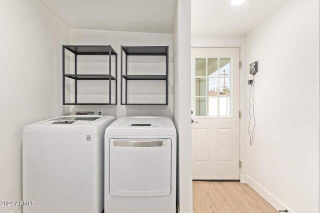 clothes washing area featuring independent washer and dryer and light hardwood / wood-style flooring